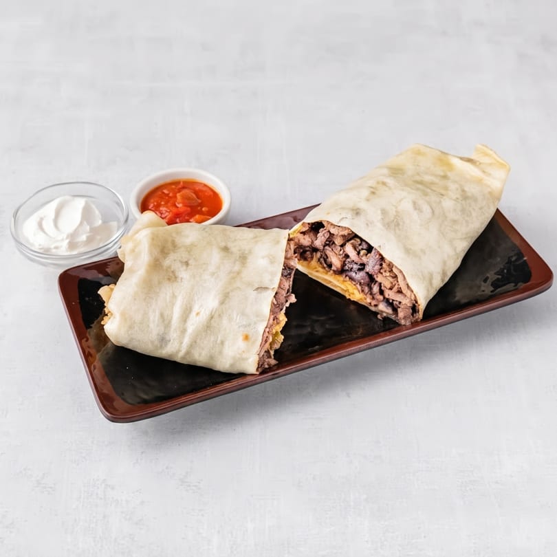 A large burrito, cut in half, revealing meat and cheese, served with salsa and sour cream.